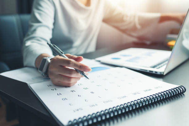 Person writing a daily plan in a notebook at a tidy desk
